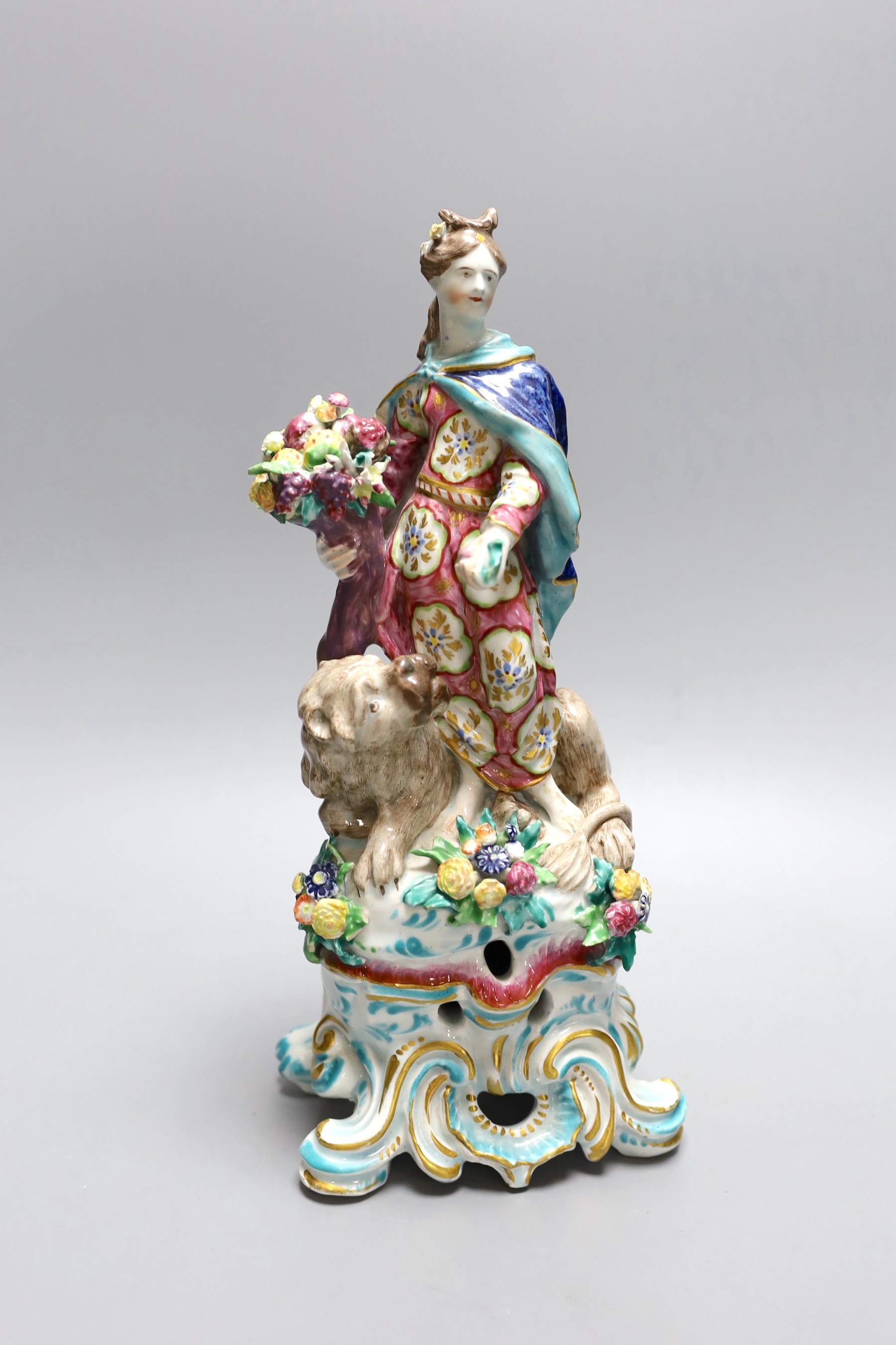 A Bow figure of Plenty, a caped woman sanding holding a cornucopia full of fruit beside a well modelled lion, c.1765, 28cm